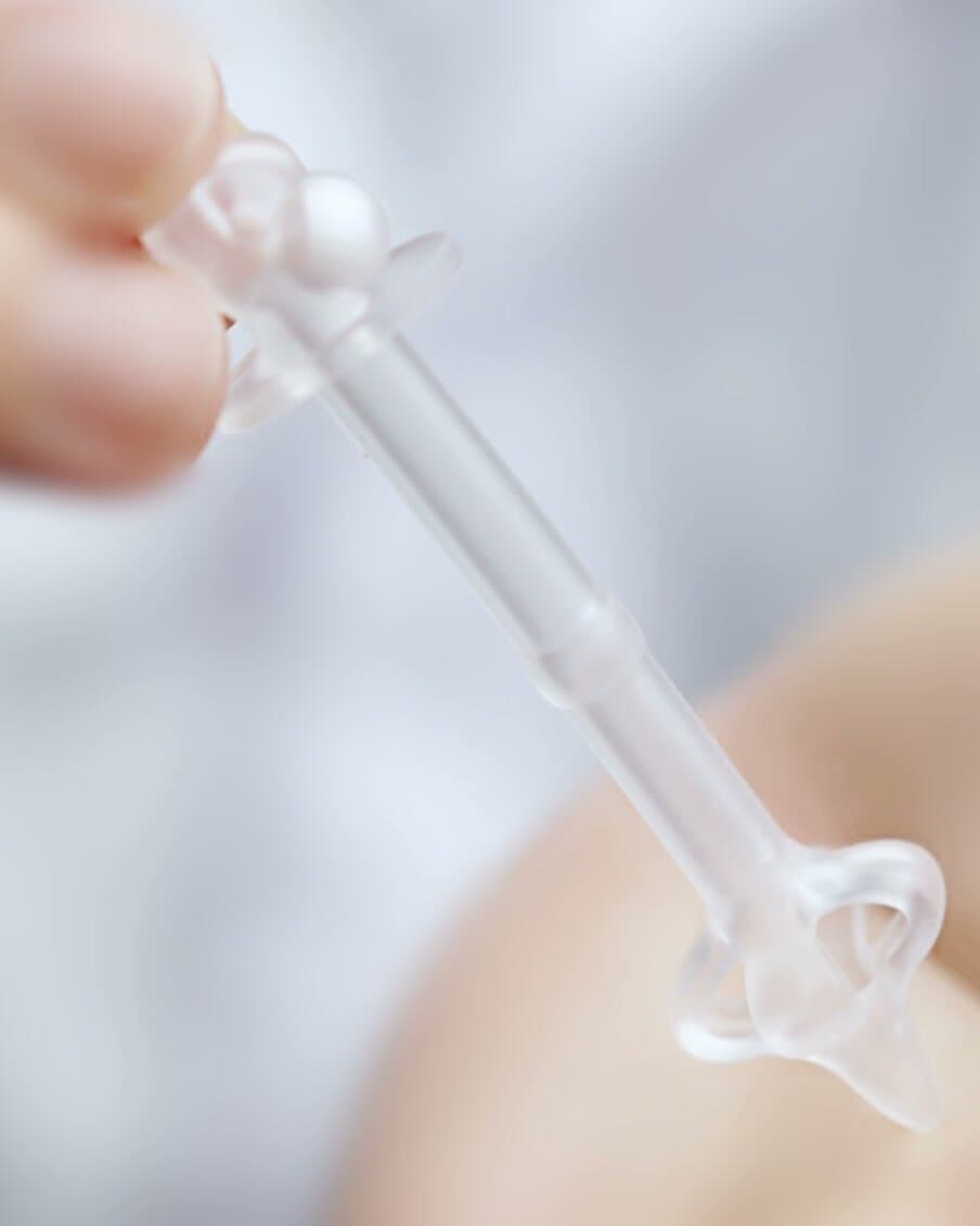 The Disposable Sterile Controlled Catheter held between two fingers, showing the ball-bead valve end, the transparent silicone shaft and the quatrefoil tip